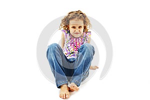 Funny little girl sitting on the floor in jeans