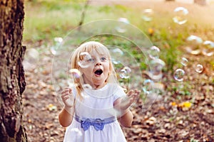 Funny little girl smile with soap bubbles in summer