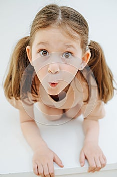 Funny little girl standing on all fours, grimacing over white backgound