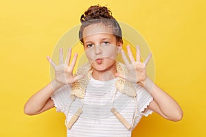 Funny little girl with wet hair wearing casual white T-shirt standing isolated over yellow background posing with poiut lips