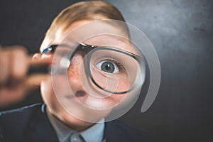 Funny little kid boy looking through a magnifying glass. Big eye.