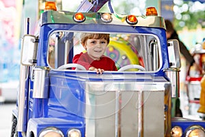 Funny little kid boy riding on a merry-go-round carousel