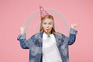 Funny little kid girl 12-13 years old in denim jacket birthday hat isolated on pastel pink background in studio