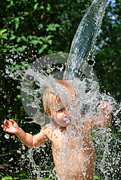Funny little kid is poured with cold water from bucket. Water games on hot day in backyard. Hardening for health. Strengthen your