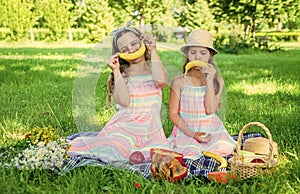 Funny little kids make sad and happy smiley emoticons with banana fruit at picnic on green grass on sunny summer