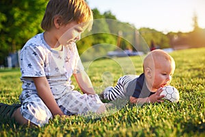 Funny little kids playing with ball on green grass on nature at summer day. Two brothers outdoors. Preschool boy and baby boy. Chi