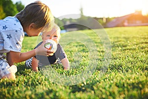 Funny little kids playing with ball on green grass on nature at summer day. Two brothers outdoors. Preschool boy and baby boy. Chi