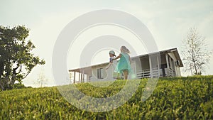 Funny little kids running on green lawn and holding colored windmill toy