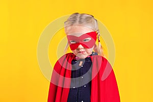 Funny little power superhero child girl in a red raincoat and a mask. Superhero concept.