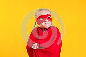 Funny little power superhero child girl in a red raincoat and a mask. Superhero concept.