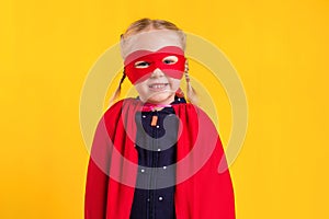 Funny little power superhero child girl in a red raincoat and a mask. Superhero concept.