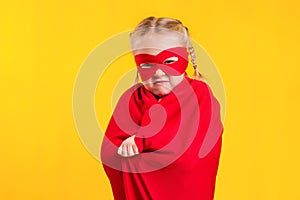 Funny little power superhero child girl in a red raincoat and a mask. Superhero concept.