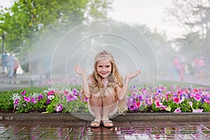 Funny little preschooler child having fun with spray of water.