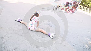 Funny Little pretty girl on roller skates in helmet riding in a park