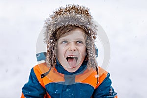 Happy kid boy having fun with snow in winter