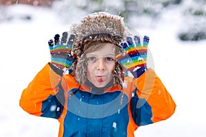 Happy kid boy having fun with snow in winter