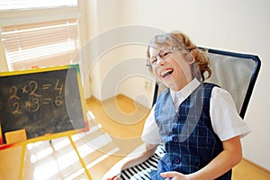 Funny little schoolboy in glasses cheerfully laughs.