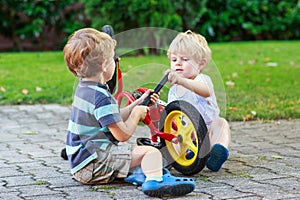 Funny little sibling boys repairing bicycle wheel