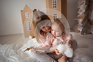 Funny little sisters (sibling) playing in a cardboard houses, l