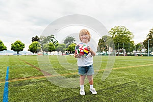 Funny little toddler boy playing on football field