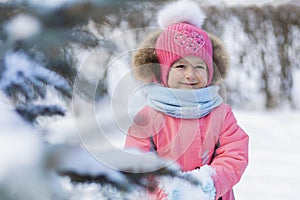 Funny little toddler girl in pink jumpsuit playing in snowballs. wintertime for children. winter games outdoors.