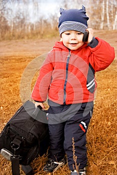 Funny little traveler with a bag and a cell-phone