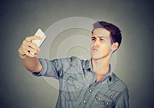 Funny looking man taking pictures of himself with smartphone