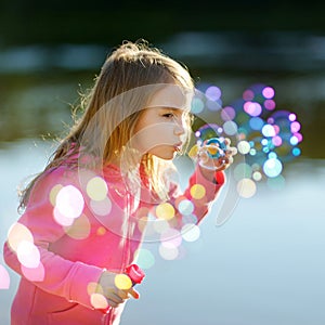 Funny lovely little girl blowing soap bubbles