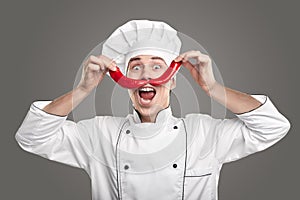 Funny male chef creating imaginary mustache with red chili peppers