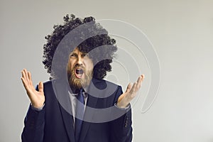 Funny man in afro hair wig angry shouting and gesturing at camera studio shot