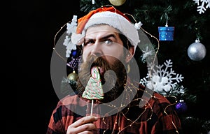 Funny man with beard on surprised face and lollipop. New year guy lick candy or sweet. Winter holiday and xmas. Party