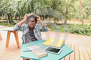 Funny man with book on head sitting in outdoor cafe