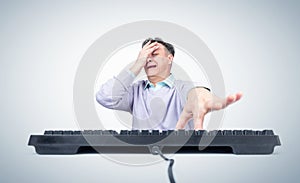 Funny man in casual clothes scared while making a facepalm and presses a key on a computer keyboard, on light background