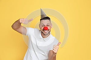 Funny man with clown nose and party hat on background. April fool`s day