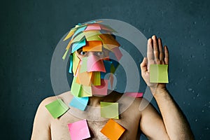 Funny man with colorful sticky notes all over his face and body show palm hand