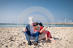 Funny man in elegant suit and horse-head mask with young woman
