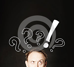 Funny man face with hand drawing question marks on blackboard background