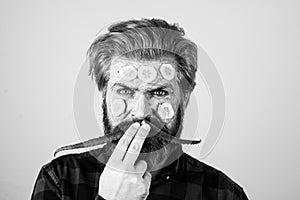 Funny man with facial mask with Cucumber and aloe vera having fun. Spa man applying facial clay mask. Funny bearded man