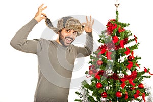 Funny man with fur hat near Xmas tree