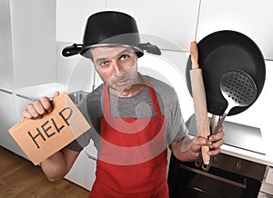 Funny man holding pan with pot on head in apron at kitchen asking for help