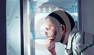 Funny man looking into refrigerator