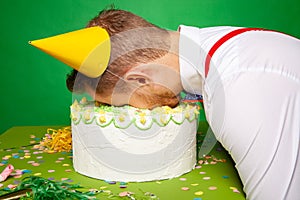 Funny man lying with face in birthday cake