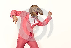 Funny man in a pink suit and a dinosaur mask dancing and having fun at a crazy party