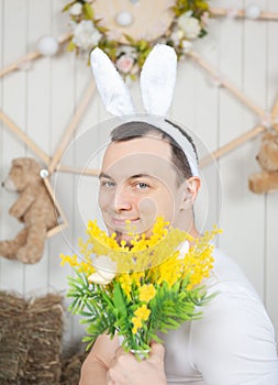 Funny man with rabbit ears holding flowers Easter holiday concept