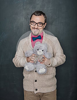 Funny man in retro style with teddy bear toy on blackboard background