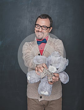 Funny man in retro style with teddy bear toy on blackboard background