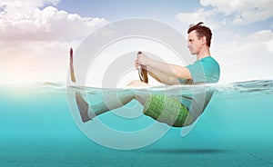 Funny man in shorts, T-shirt and flippers rides on the sea with a car steering wheel. Concept of going on vacation