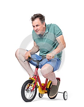 Funny man in shorts and a t-shirt rides a children`s bicycle, isolated on white background.
