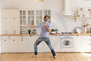 Funny man singing into kitchenware, dancing, having fun in kitchen