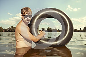 Retro man in summer lake have fun with inner tube